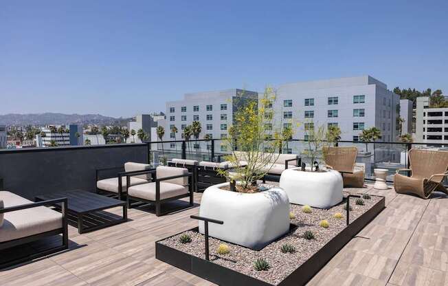 A rooftop patio with white chairs and tables at Skylar At Sunset Apartments, Los Angeles 90027