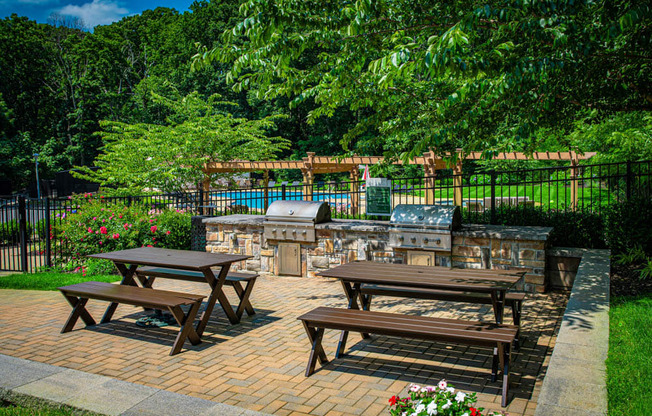 a patio with picnic tables and a pool in the background