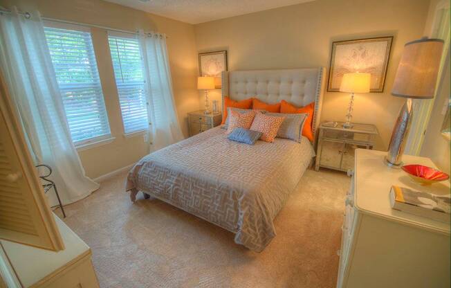 A bedroom with a large bed and a window with curtains.