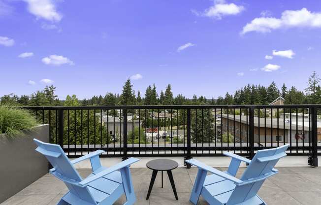 a pair of blue Adirondack chairs in the rooftop lounge area overlooking the view with a table and stool at Arabella Apartment Homes, WA 98155