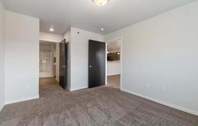 a living room with carpet and white walls and a black door