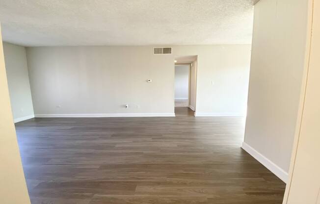 an empty living room with wood floors and white walls