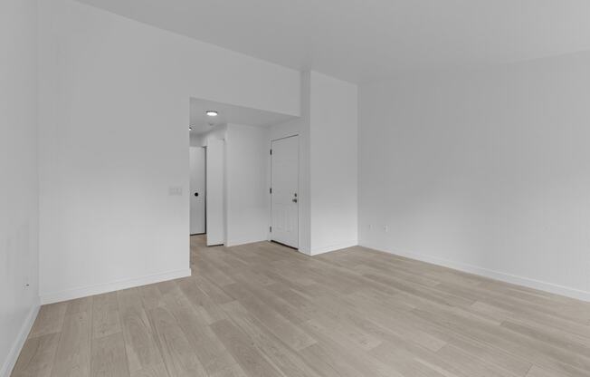a living room and bedroom with white walls and wood flooring