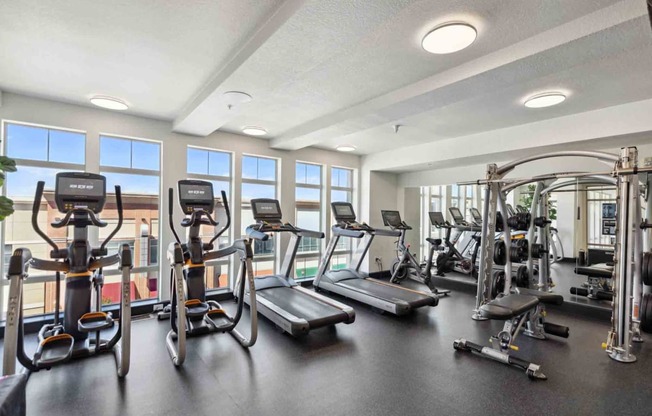 a gym with cardio equipment and windows in a building