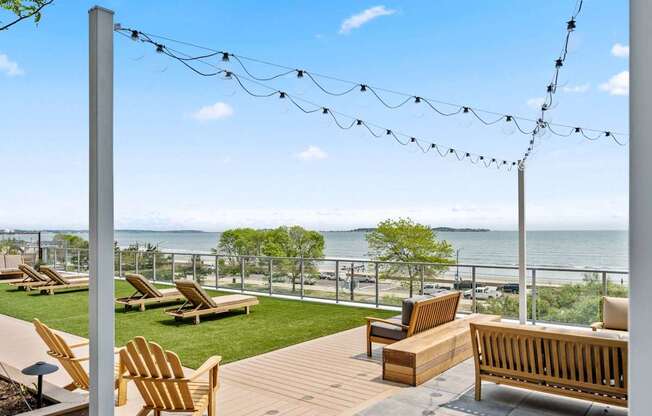 A wooden deck with chairs and a bench overlooking the water.