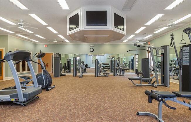 a gym with cardio machines and weights and a tv at Bedford Parke Apartments, Warner Robins