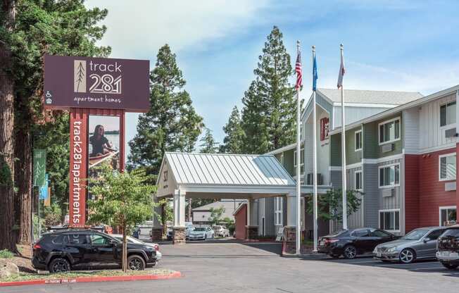 a hotel with a sign and cars parked in front of it