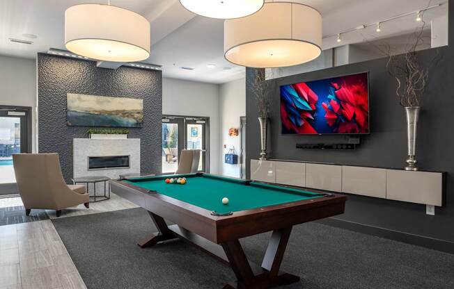 A room with a pool table and a television mounted on the wall.
