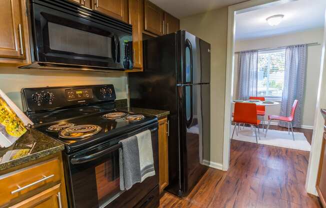 a kitchen with black appliances and wood flooring at Broadway at East Atlanta, Atlanta, GA