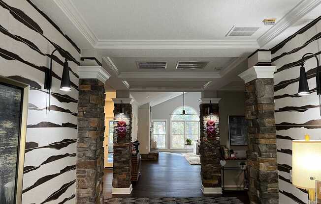 A hallway with a striped wallpaper design and stone pillars.