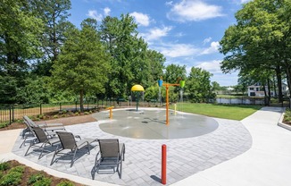 A playground with a round concrete structure and chairs.