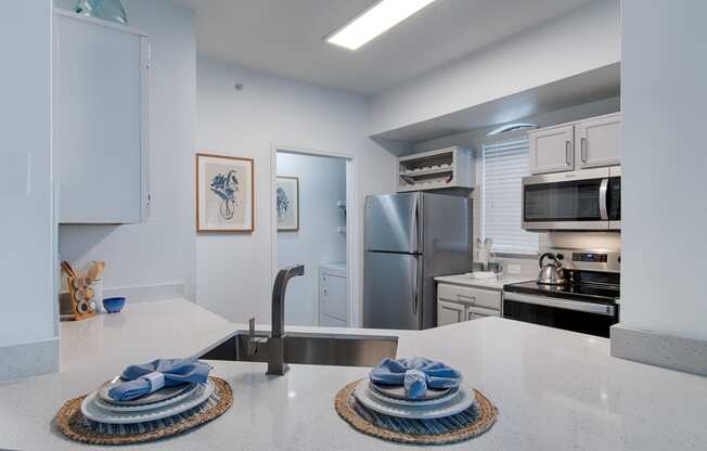 a kitchen with white countertops and stainless steel appliances