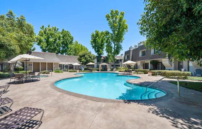 a swimming pool with chairs and umbrellas and a building in the background