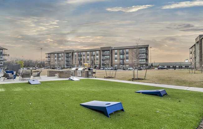 A grassy area with a blue object in the middle and apartment buildings in the background.