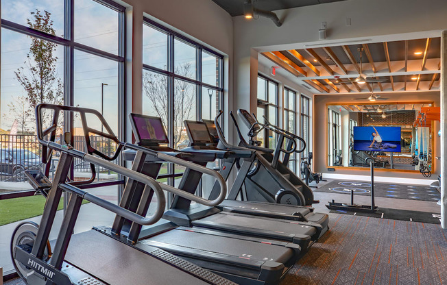 the gym at the monarch club has cardio equipment and large windows