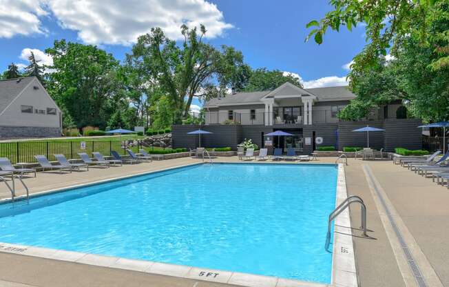 a swimming pool with chairs and a building in the background