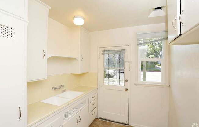 A small kitchen with white cabinets and a white door.