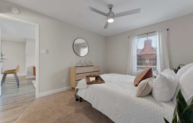 A bedroom with a white bed and a window with white curtains.