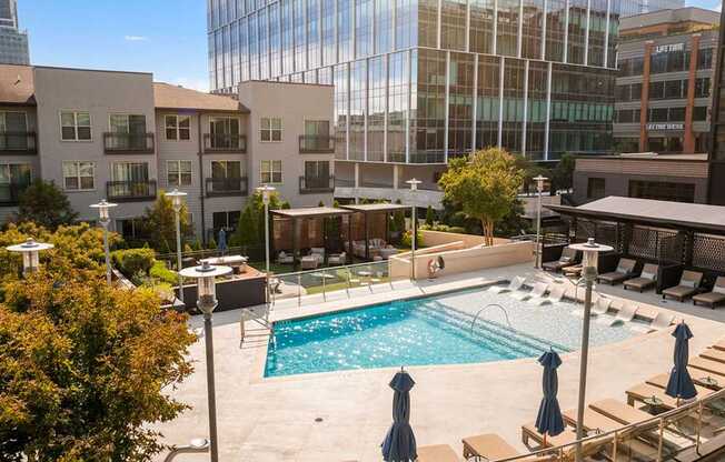 A swimming pool surrounded by a patio with chairs and umbrellas.