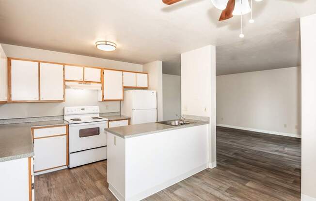 A kitchen with white appliances and wooden floors.