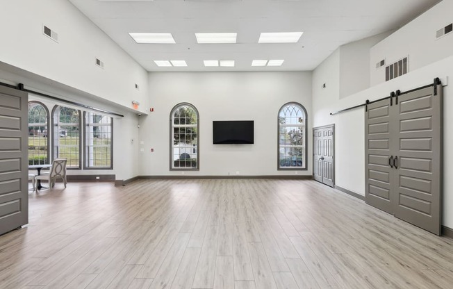 an empty room with white walls and wood floors and a wall mounted tv