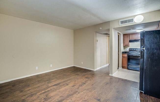 A kitchen area with a black fridge and wooden floors.