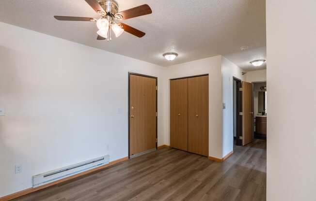 an empty living room with a ceiling fan and a closet. Fargo, ND Eagle Run Apartments