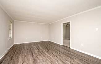 A room with a wooden floor and a doorway leading to another room.