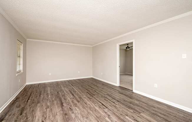 A room with a wooden floor and a doorway leading to another room.