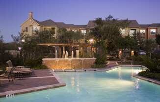 a large swimming pool with a waterfall in front of a large house