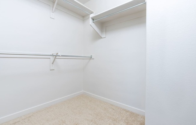 a empty room with a white wall and a hanging rail in a closet