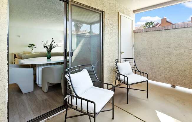 a small balcony with two chairs and a table