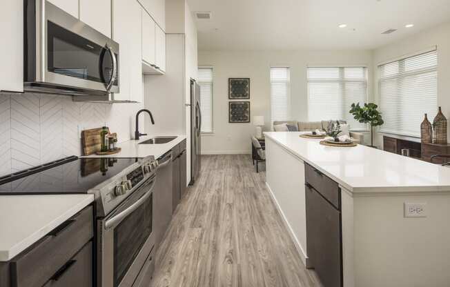 an open kitchen and living room with a large island and a stove and a microwave