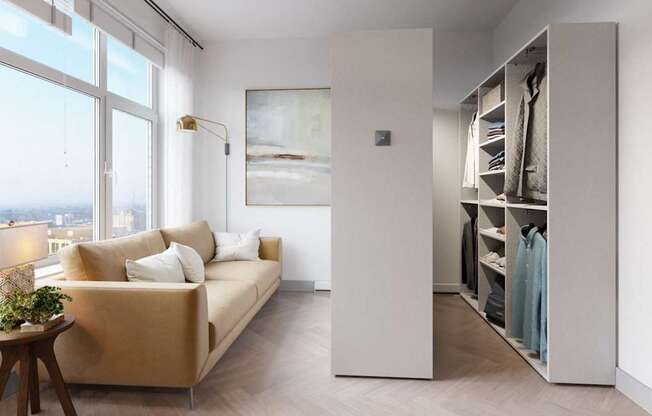 A room with a tan couch, a wooden table, and a large window overlooking the city.