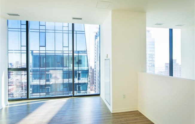 an empty room with white walls and floor to ceiling windows with a view of the city at One 333, Chicago, 60605