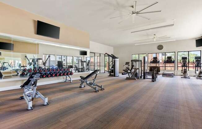 A gym with a variety of equipment including weights and cardio machines.