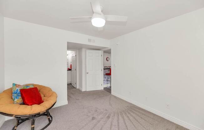 A room with a ceiling fan and a round chair with a red pillow at Urban WalkApartments on 6th Avenue, Phoenix, Arizona