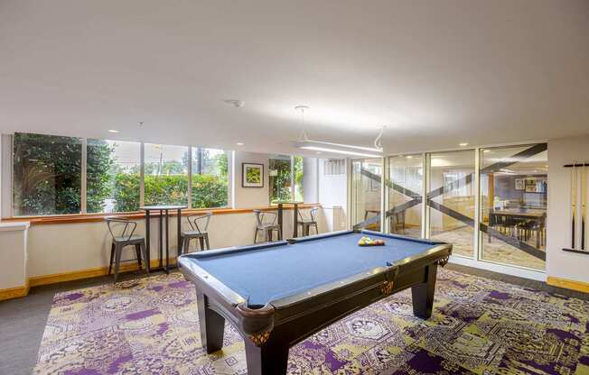 A pool table in a room with a view of the backyard.