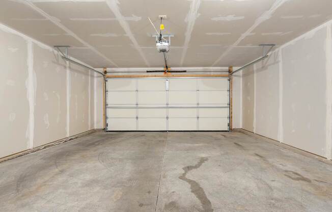 A garage with a white door and a concrete floor.