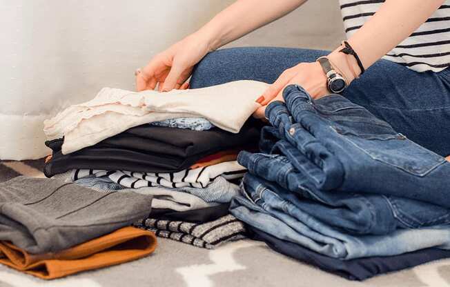 a woman sitting on the floor with a pile of clothes