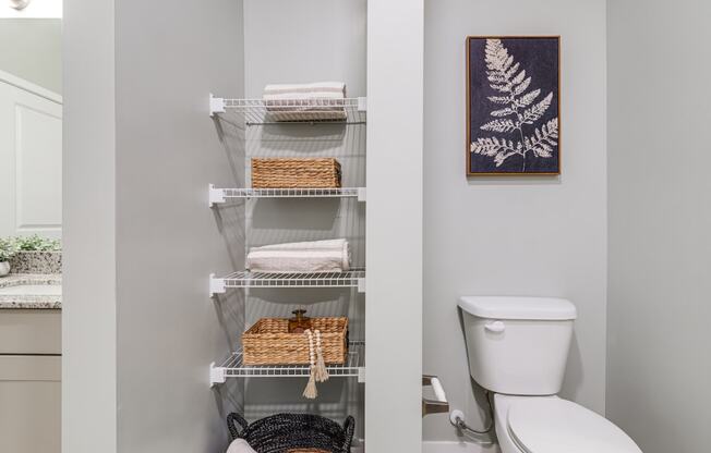 a bathroom with a toilet and a shelf with towels