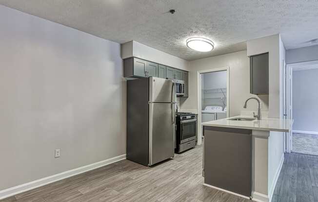 an empty kitchen with a stainless steel refrigerator and a counter top