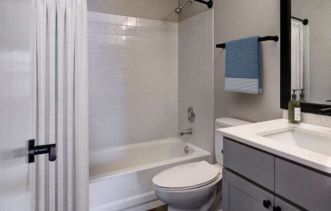 A white toilet sits in a bathroom next to a bathtub.