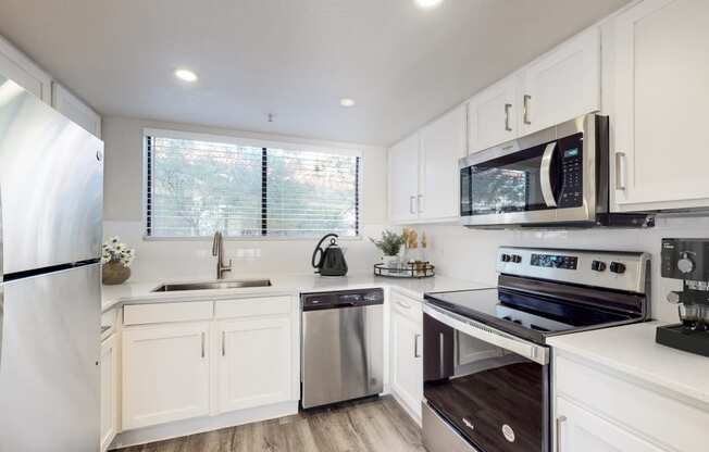 a kitchen with white cabinets and stainless steel appliances