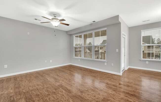 an empty living room with a ceiling fan and a window