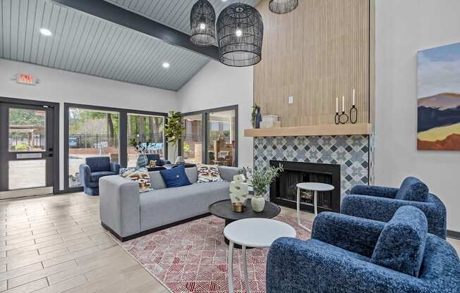 A living room with a grey couch, blue chairs, and a fireplace.