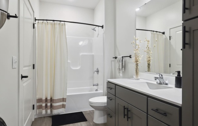 a bathroom with a white sink and toilet next to a white bathtub with a shower curtain
