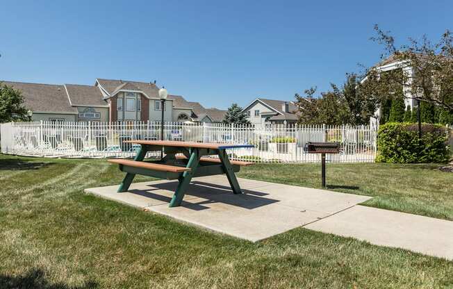 A green picnic table sits in the middle of a grassy area.
