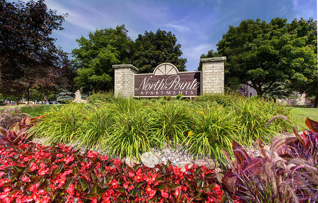 A sign for North Point Apartments is surrounded by flowers and greenery.