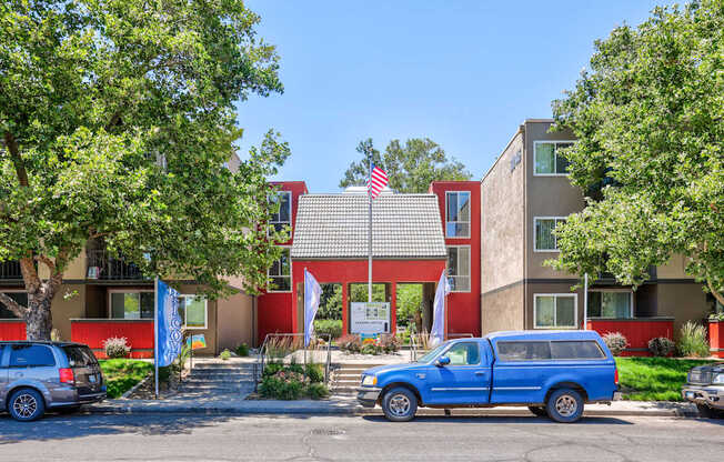 A blue van is parked in front of a building with an American flag on it.